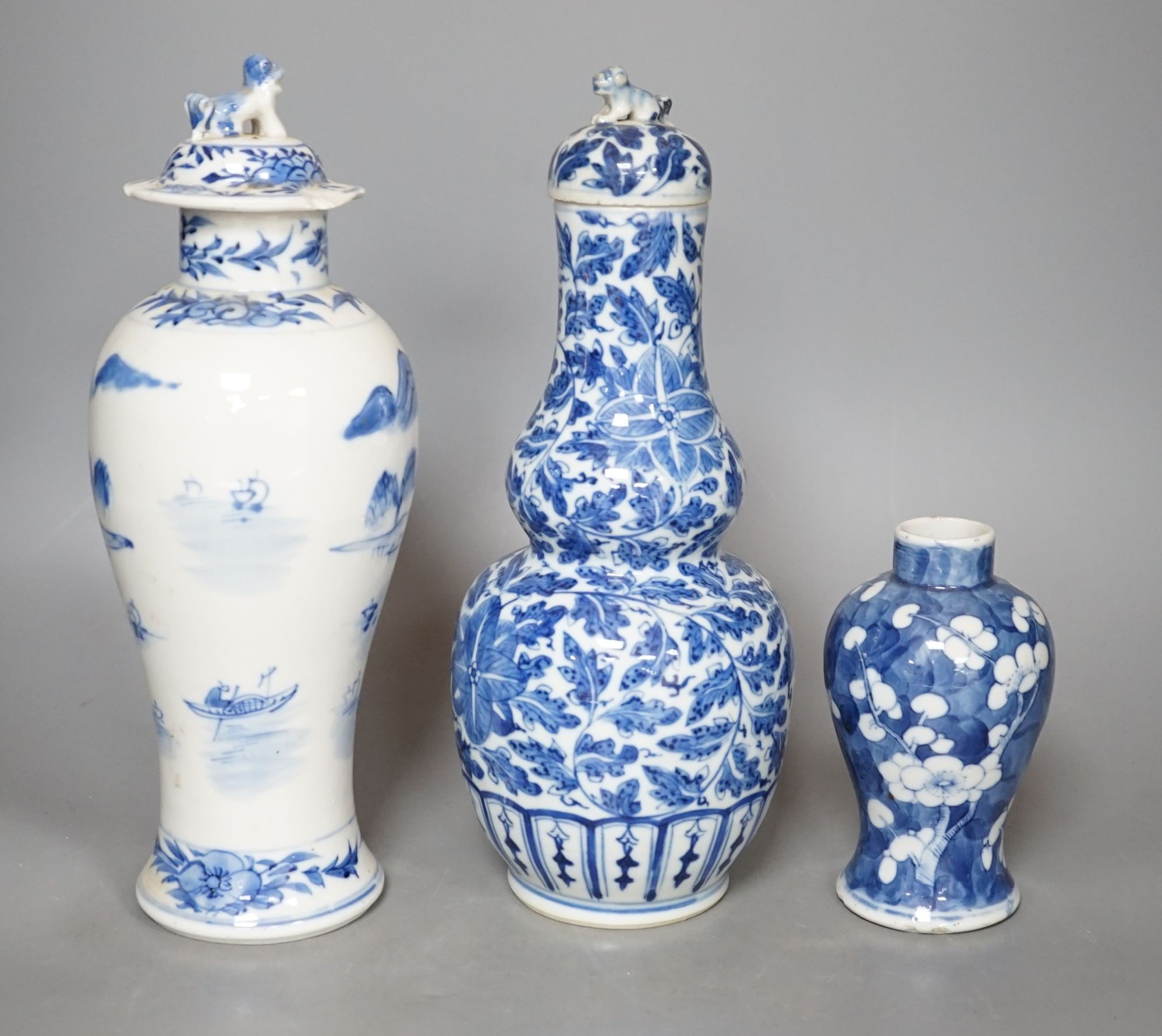 A Chinese double gourd vase and cover, a similar vase and cover and a prunus vase, all 19th century, tallest 28 cms high.